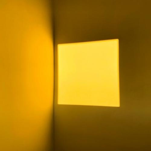 A square outlined by shadows on a yellow wall.