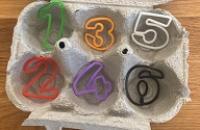Plastic numbers from 1 to 6 inside an egg carton.