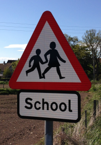 A school crossing sign in a red triangle.