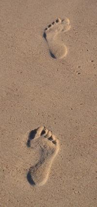 Two footprints left in wet sand.