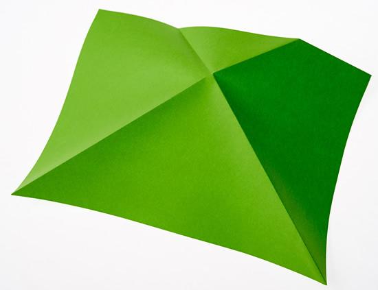 A sheet of paper, folded from each of the bottom corners to 2 points on the opposite side, with the folds crossing over in the middle.