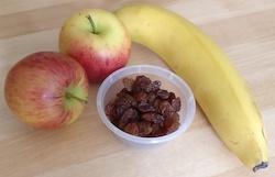 Two apples, a banana and a pot of raisins.