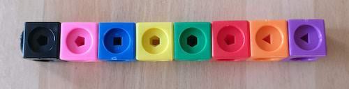 A stick made of a black, pink, blue, yellow, green, red, orange and purple cube from left to right.