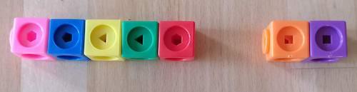 The stick on the left is made of a pink, a blue, a yellow, a green and a red cube. The stick on the right is made of an orange and a purple cube.