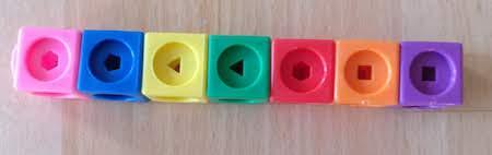 A stick of cubes. From left to right, they are pink, blue, yellow, green, red, orange, and purple.