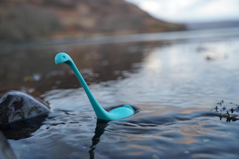 A blue plastic Loch Ness monster toy in a lake.