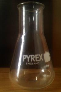 A tube which has a flat circular base, which decreases in size as you move up, and eventually maintains a cylindrical shape until the top.