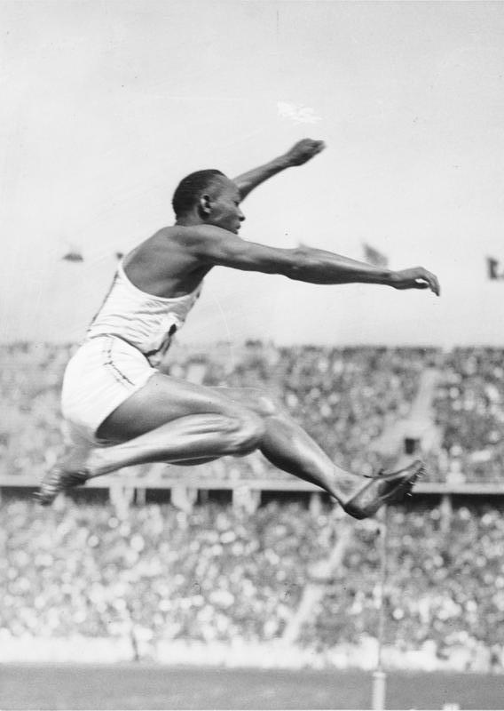 Jesse Owens in mid-air during a long jump.