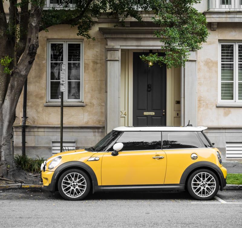 A house with a yellow car outside it.