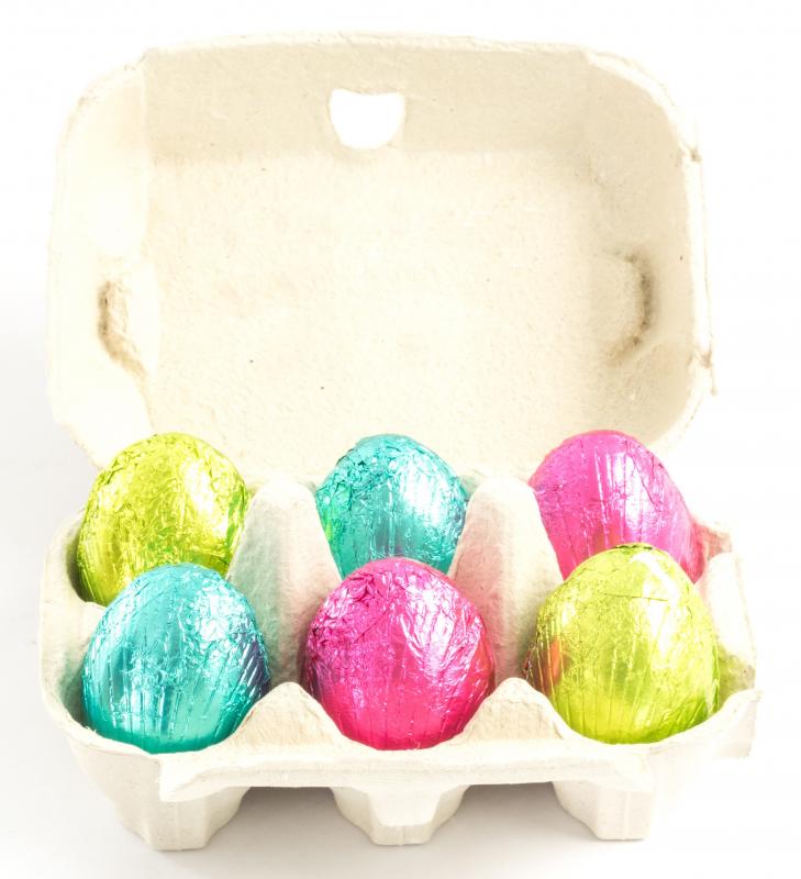 Six colourfully wrapped chocolate eggs in an eggbox.