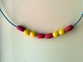 A necklace of beads. From left to right, the beads are: red, yellow, yellow, red, red, yellow, yellow, red.