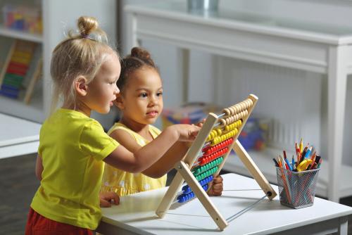 Two young girls wearing yellow playing with an abacus.
