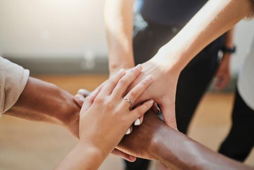 The hands of five people, all on top of each other.