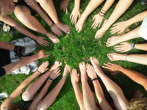 Lots of people's hands and arms all reaching out towards a central point.