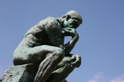 Rodin sculpture of a man thinking, his arm resting on his knee and chin resting on his hand.