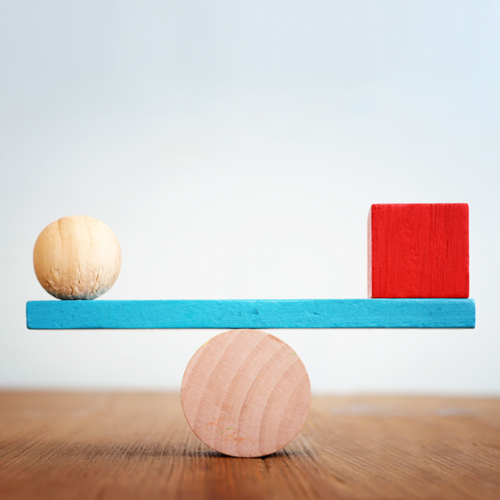 A wooden ball and wooden block, balancing on a wooden balance.