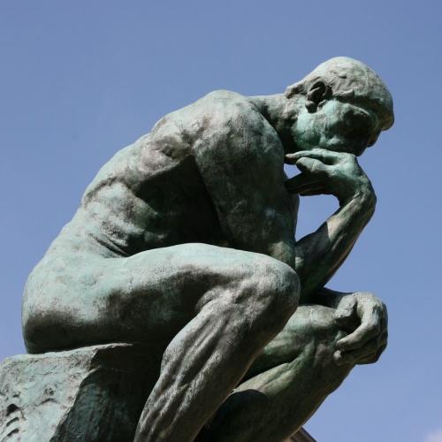 Rodin sculpture of a man thinking, his arm resting on his knee and chin resting on his hand.