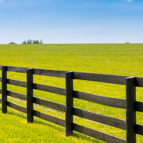 A wooden fence beside a green field.