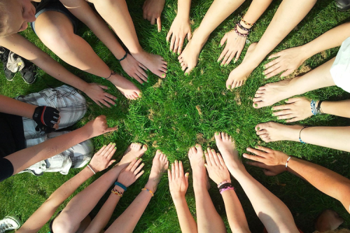 Lots of people's hands and arms all reaching out towards a central point.
