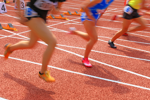 Athletes running from the starting blocks of a track.