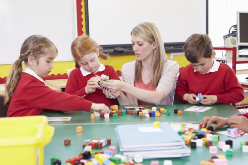 Three children and a teacher using multilink cubes.