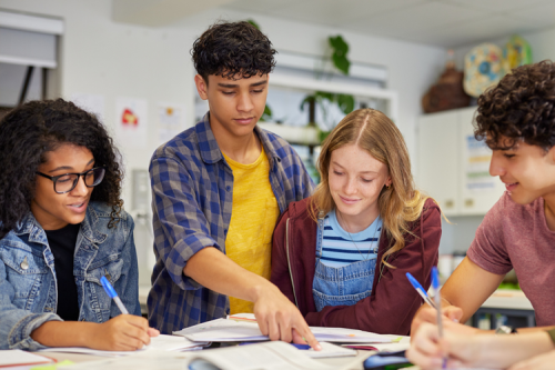 Four teenagers working together from books at a table.