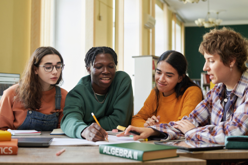 Four teenagers of different ethnicities working on algebra together.