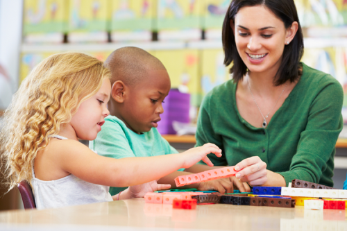 Two children and their teacher looking at sticks of linking cubes.