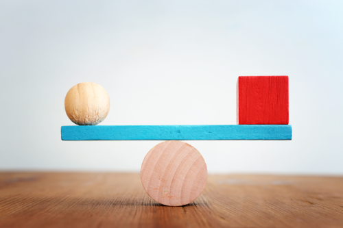 A wooden ball and wooden block, balancing on a wooden balance.