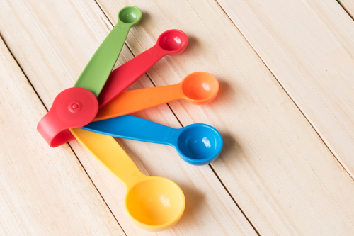 Colourful plastic measuring spoons on a wooden table.