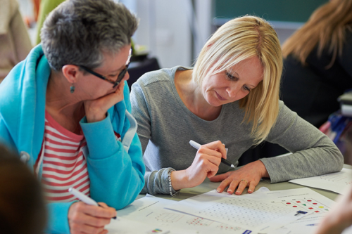 Two women looking at maths together at a table.