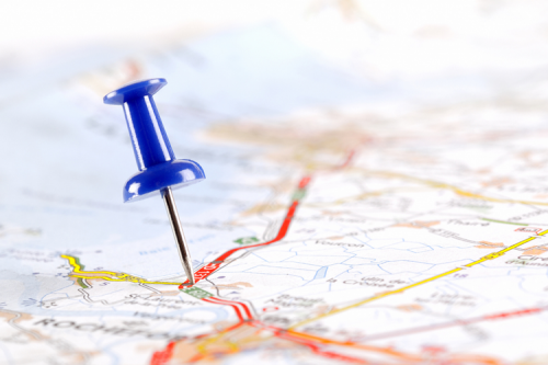 A blue pin on a paper map.