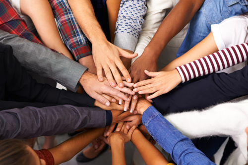 Hands of a variety of people overlapping.