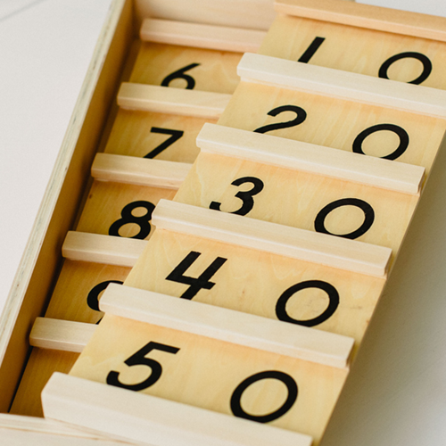 Wooden slots showing two-digit numbers in the ten times table.