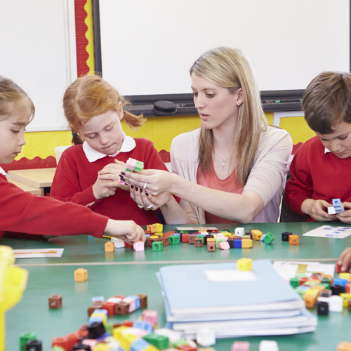 Three children and a teacher using multilink cubes.